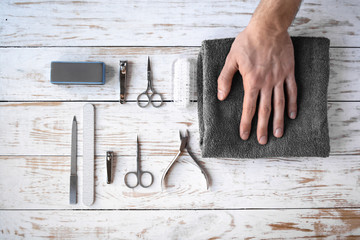 Nail cutter, file, scissors, brush and other manicure tools and instruments. Flat lay hygiene accessories. Male hand on a gray towel.
