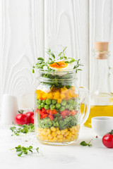 Fresh salad in jar with soft boiled egg, liquid yolk. Corn, green lettuce, bell pepper, peas. Delicious food, healthy lunch