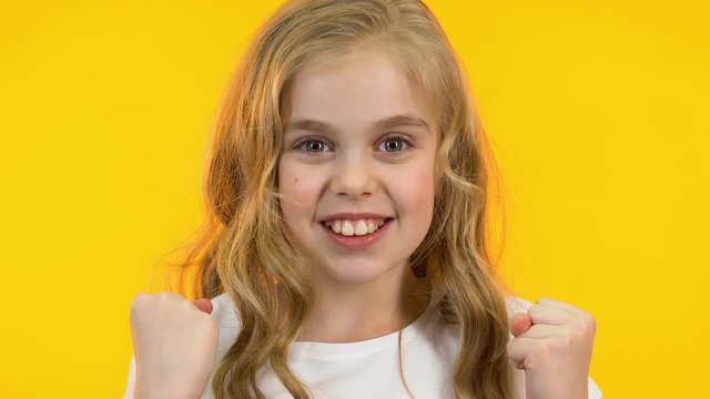 Cute little girl showing yes gesture, success, pleasure emotions, close-up