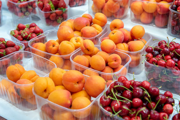 Fruits - apricots, cherries, strawberries on the counter of the stall. Food market.