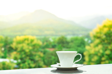 White glass of coffee with mountain and natural background at sunrise, beverage in relaxing