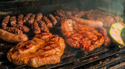 Juicy pork steaks, sausages and minced meat cevapcici on charcoal barbecue.