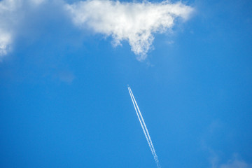 Airplane flying high over white clouds leaving white trails.