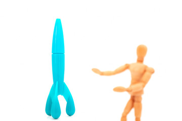 blue plastic space craft and blurred wooden figure on white background, explorer and education...