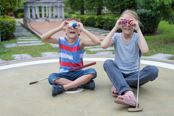 Happy brother and sister playing mini golf