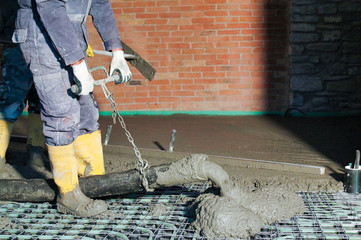 man  pours concrete  over floor heating system