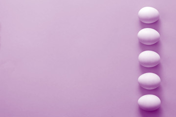 Easter eggs and flowers tulips on purple background. From above, copy space, flat lay