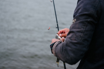 The fisherman rotates the hand reel on a spinning close-up