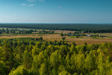 Panoramic high angle view of the plain, the village and the woods from hill top.