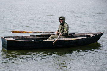 A man is rowing in a wooden boat