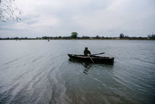 A man is rowing in a wooden boat