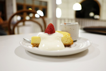 Strawberry cheesecake with dipping sauce on white table.