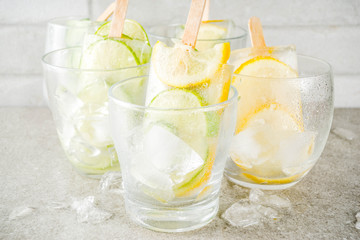 Healthy diet summer dessert, Vegan trendy ice cream. Sweet and sour infused water popsicles with cucumber, lime and lemon slices, Grey stone background copy space