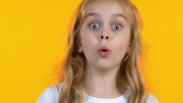 Blonde girl looking extremely shocked hearing news, isolated yellow background