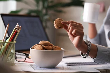 Foto op Aluminium Cloe up of businesswoman eating cookies in the office. © Drazen