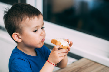 baby in blue t-shirt eating white bread and butter