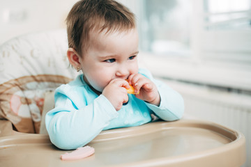 Little girl in a high chair eating cheese