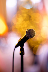Isolated bokeh microphone on a concert stage with artists redy to perform in the backstage