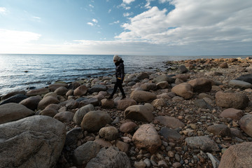 Young archaeologist on a boulder beach looking for exotic rocks on a coastline of a Baltic Sea