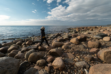 Fototapeta na wymiar Young archaeologist on a boulder beach looking for exotic rocks on a coastline of a Baltic Sea