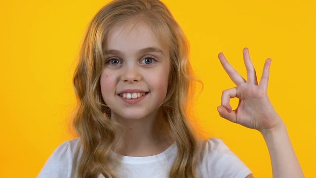 Cheerful girl winking showing ok sign, happy with goods for children, close-up