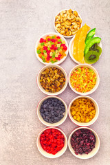 Dried and candied fruit and cashew nuts. Assorted in ceramic bowls on a stone background. Healthy vegetarian (vegan) food concept, top view, close up.