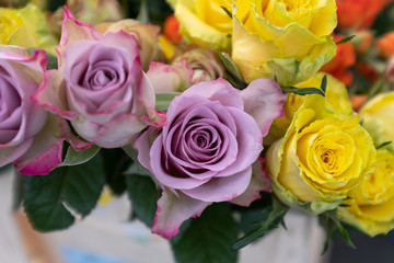 A top down view of bunches of multi-coloured roses for sale at a local market, including pink, red and yellow