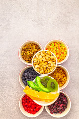 Dried and candied fruit and cashew nuts. Assorted in ceramic bowls on a stone background. Healthy vegetarian (vegan) food concept, copy space, top view.
