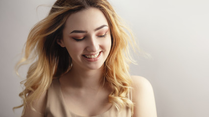 studio portrait of a beautiful sincerely laughing girl, young woman face with curly hair disheveled from wind , the concept of natural beauty, body care, cosmetics