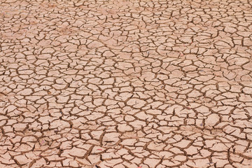 Deep cracks earth in the red land as a symbol of hot climate and drought.