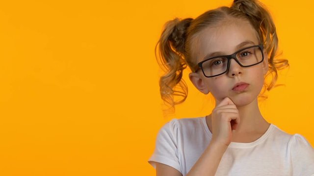 Little nerd girl in eyeglasses thinking about task decision or future career