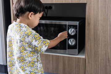 A boy is cooking his breakfast by microwave .