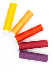 Fototapeta na wymiar sewing threads in yellow, orange, red and purple isolated on white background, arranged in a semicircle