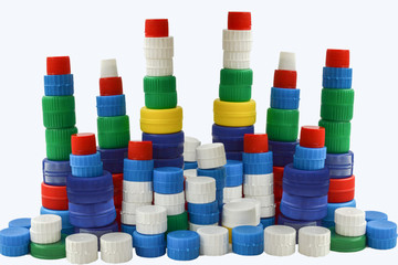Tower of colorful plastic bottle caps simulating a city with skyscrapers isolated on white background
