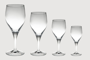 four crystal wine glasses in decreasing size isolated on white background