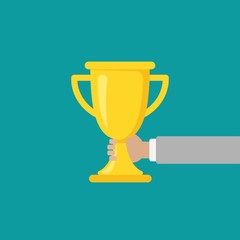 Hand with gold trophy, winning cup isolated on blue background. First place, award bowl.