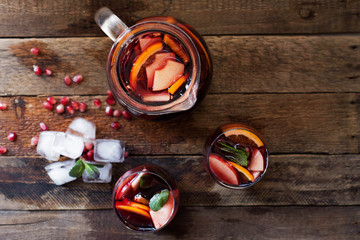 Refreshing homemade lemonade with ice, pomegranate, orange and mint. on a wooden table.