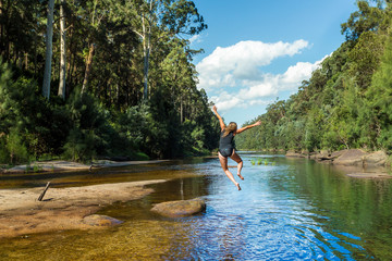 Active Aussie woman jumping into river remote bushland