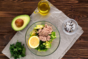 Salad with tuna, avocado, salt,  parsley and lemon. Top view. Organic. Vitam. Healthy food. Homemade. Wooden table. Paleo diet.