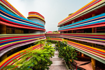  Colorful building with bundled horizontal stripes. Courtyard view on trees, stairs and floors