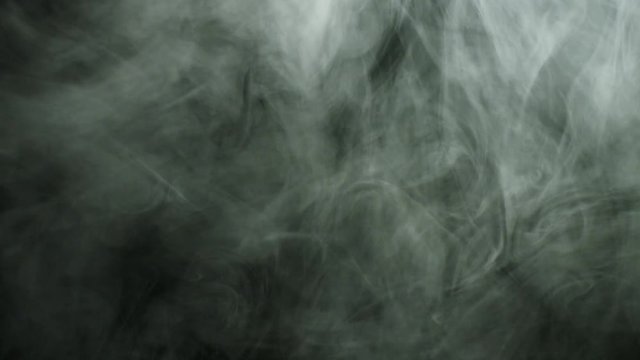 Close up for thick white smoke spreading over black background. Stock footage. Dense fog flying isolated in the dark.
