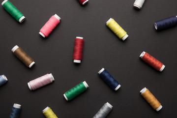 top view of scattered colorful thread coils isolated on black