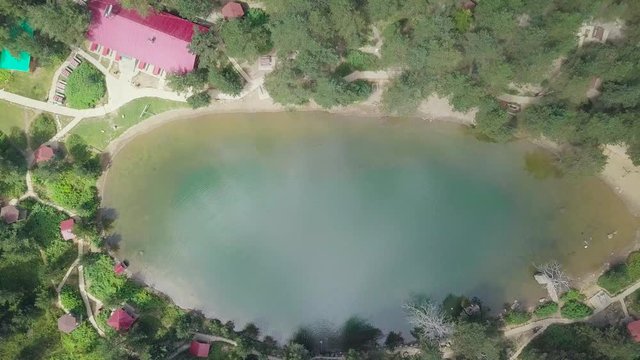 aerial zoom shot in slow motion, in bird look, a red roofed house neaby the lake, forest next to the water, in Karagol, Izmir Province, Turkey