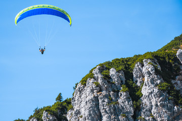 Paraglider flying dangerously close to a mountain peaks on a sunny autumn day close to the Mangart mountain range, Slovenia