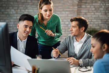 Team of entrepreneurs communicating while working on a computer during the meeting.