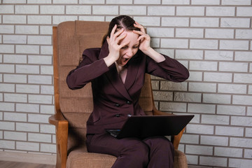 Woman in the office in depression works for a laptop.