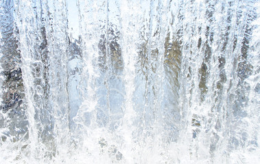 Fototapeta na wymiar Transparent blue white water pours from above. View through the water wall of the waterfall for the background.