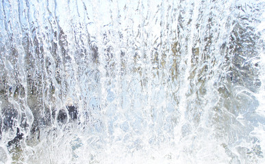 Naklejka na ściany i meble Transparent blue white water pours from above. View through the water wall of the waterfall for the background.