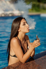 Young sexy woman is vaping. A cloud of vapor. Hot and sexy girl vaping (smoking an e - cigarette) Close-up view. Vaping concept