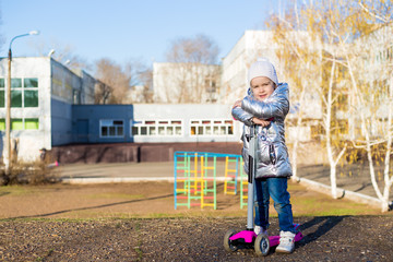 little girl riding a scooter in the Park on a Sunny spring day. Active leisure and outdoor sport...